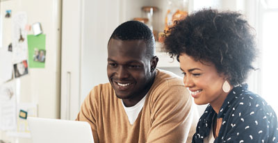 African American couple looking at their online account on their laptop